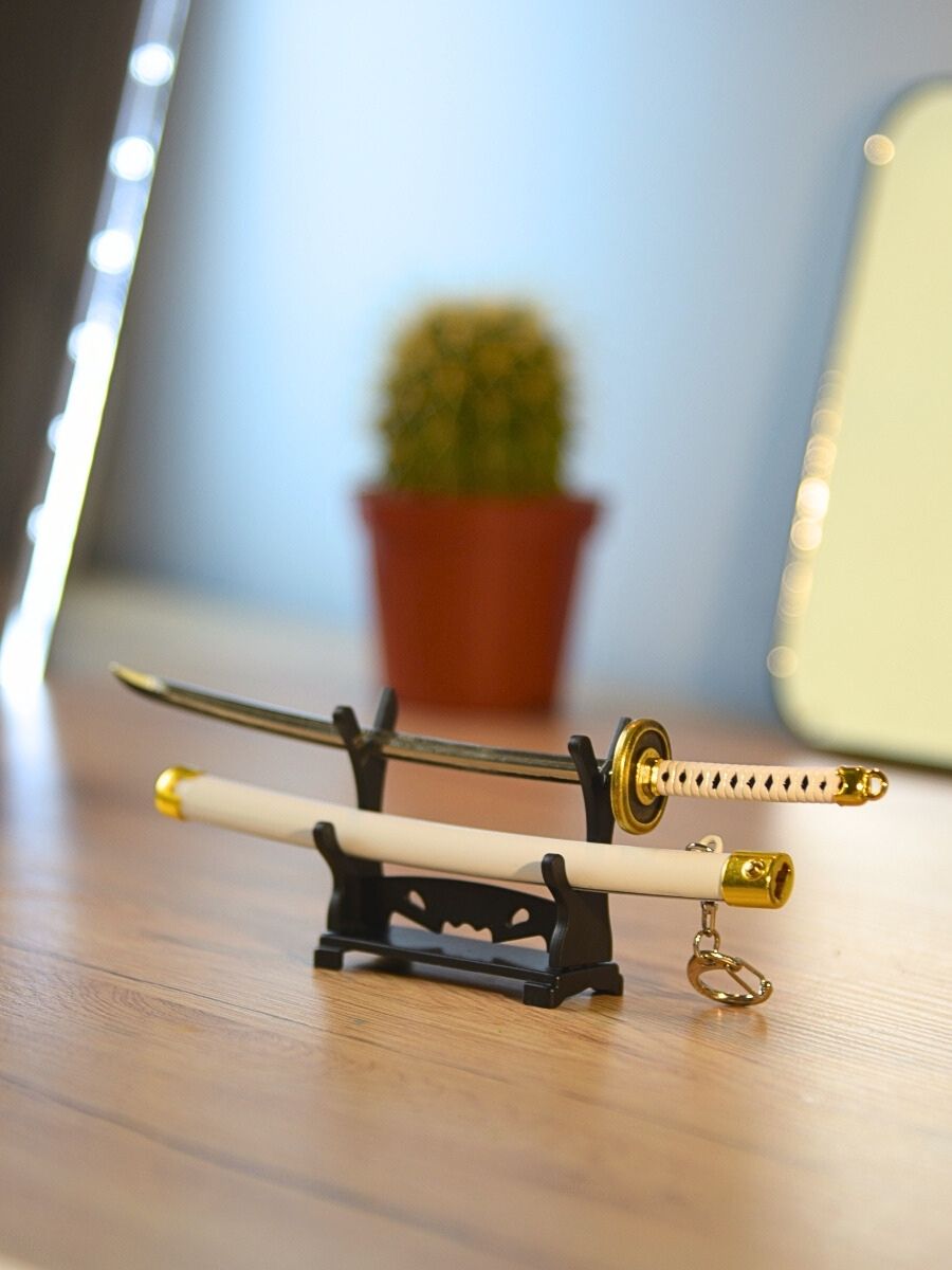 Ichimonji from One Piece miniature katana unsheathed on a stand, illuminated on a desk with a small cactus in the background.