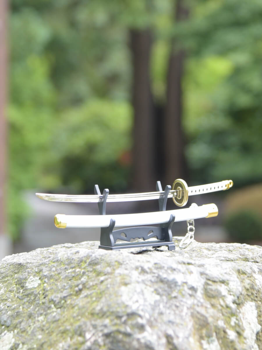 Slight blade side perspective of Ichimonji miniature katana on a stand.