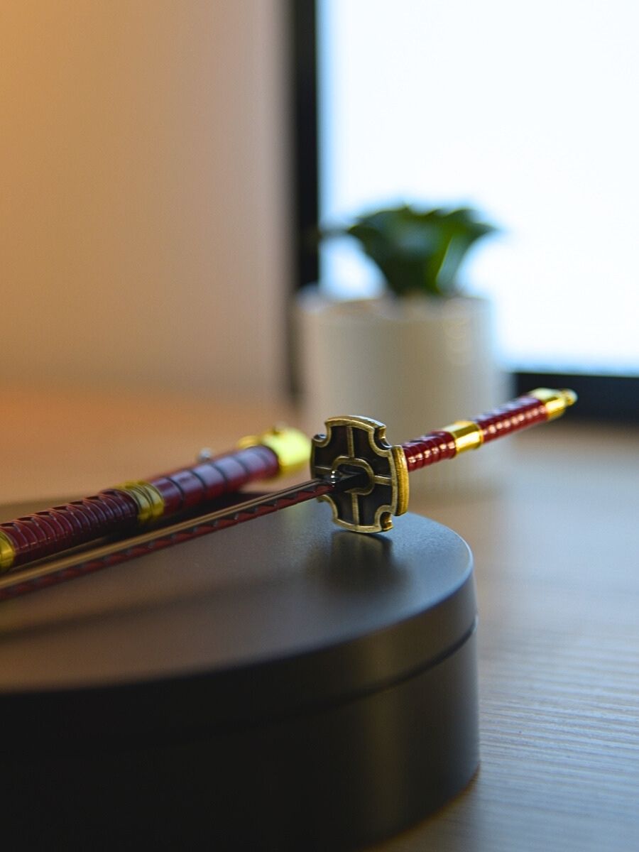 Detail of Kitetsu miniature katana handle from One Piece, resting on a black stand with a softly focused cactus in the background.