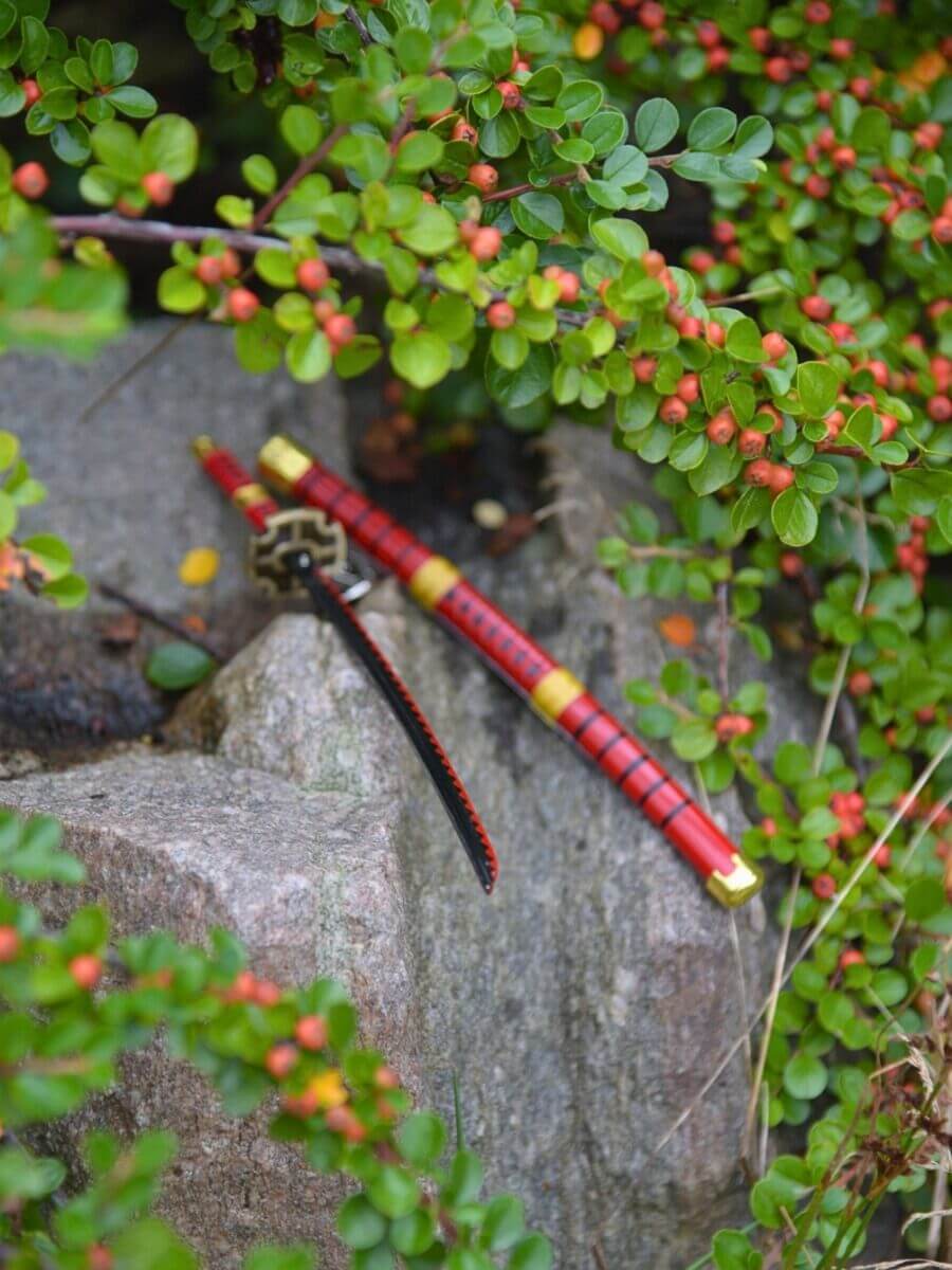 Kitetsu miniature katana tip resting on rocks amidst green plants - One Piece.