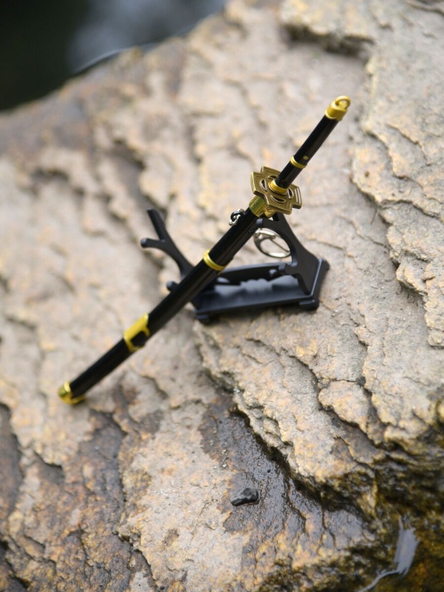Elevated diagonal view of Zoro miniature katana, perched halfway on its stand atop a rock, with glistening waters surrounding it.