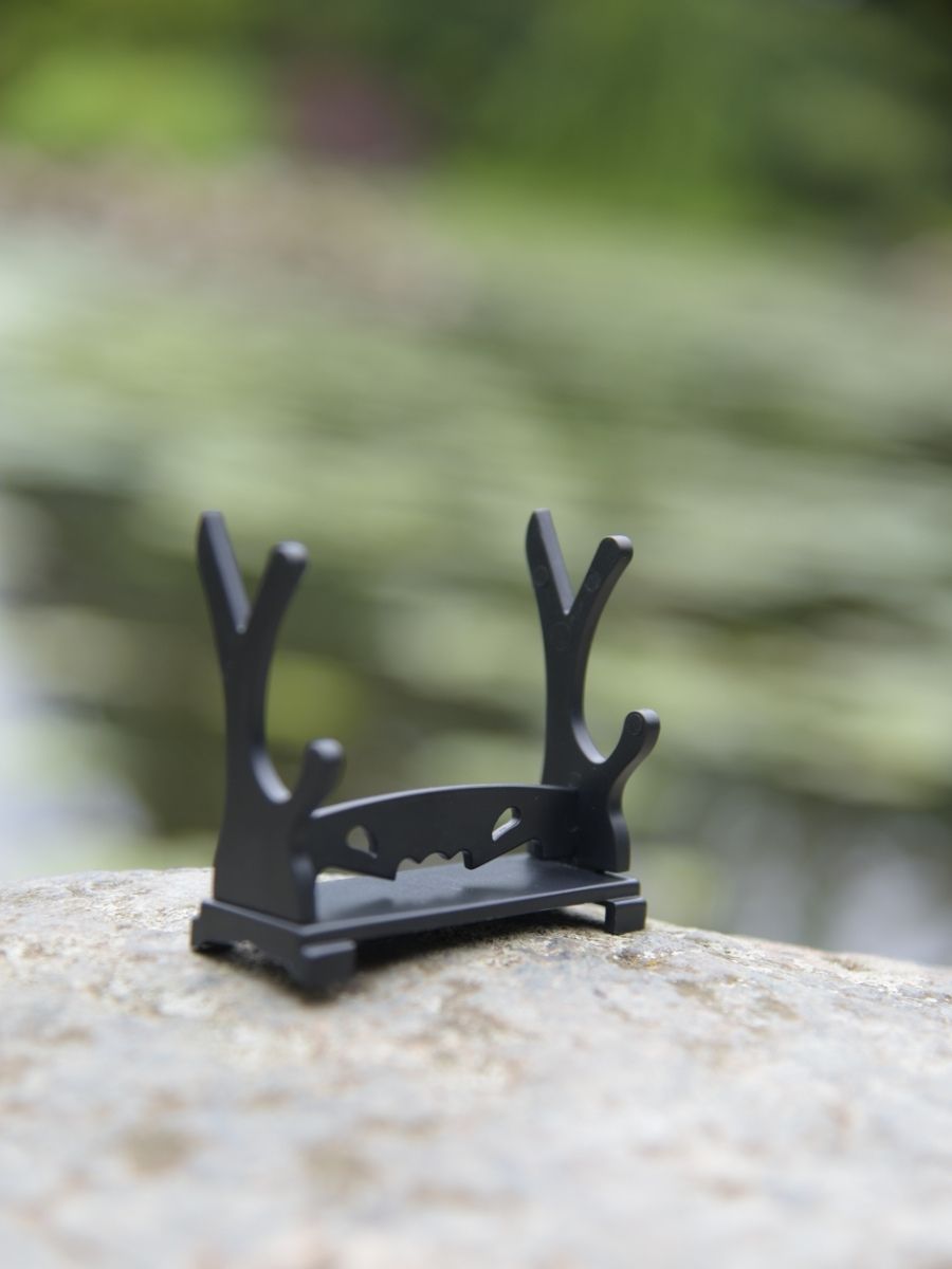 Empty stand for the One Piece Ichimonji miniature katana on a rocky surface.