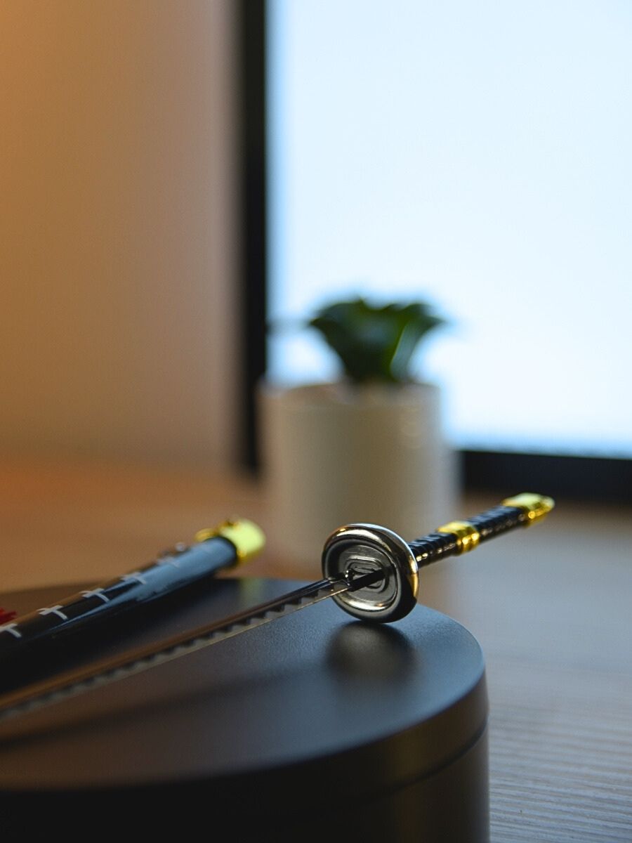 Zoomed-in view of Trafalgar miniature sword hilt, emphasizing the protective guard. The sword is set on a black stand, complemented by a softly blurred cactus in the background for a homely feel.