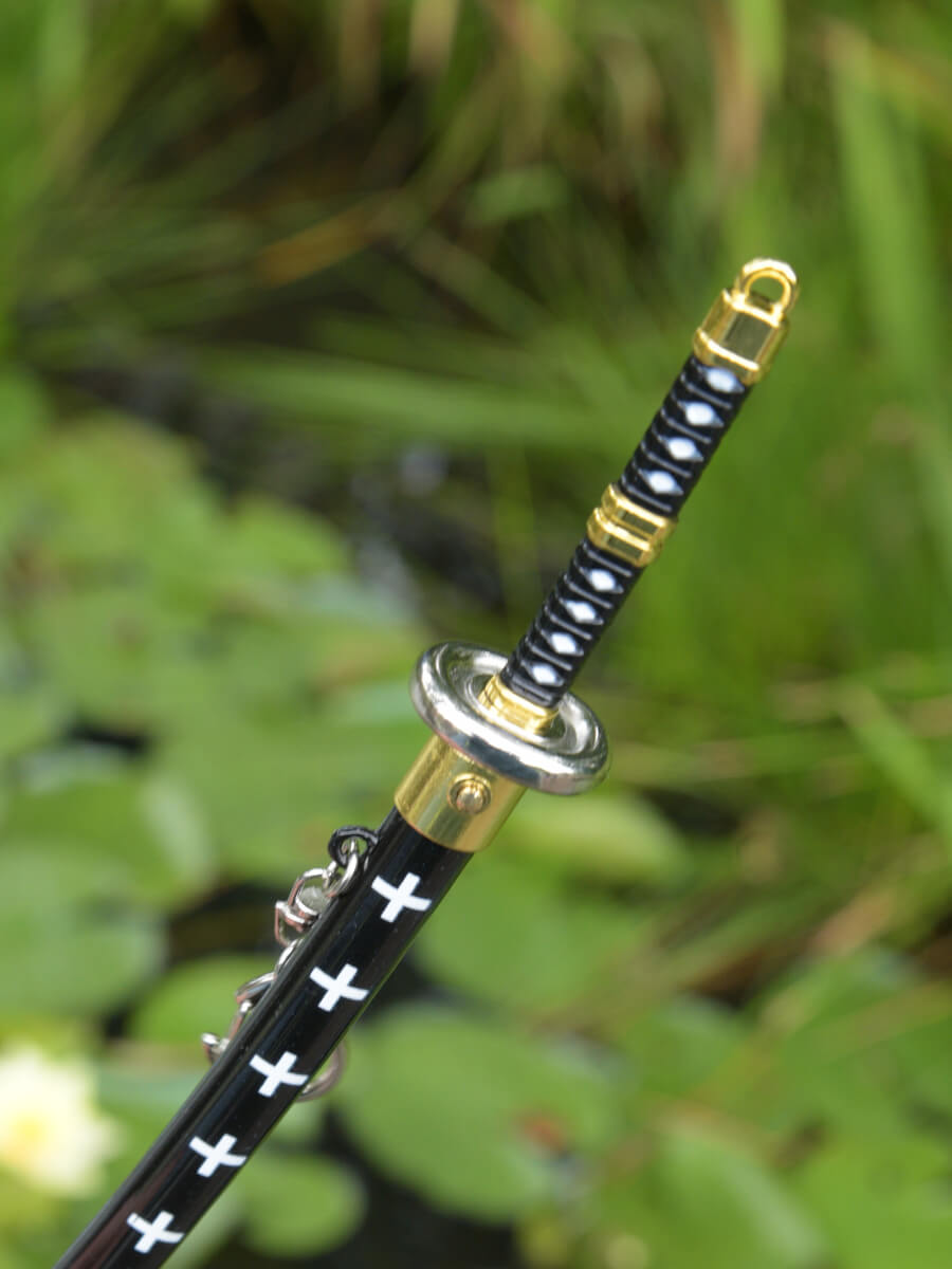 Above perspective close-up of Trafalgar miniature katana grip and a section of the scabbard, focusing on the blade release mechanism.