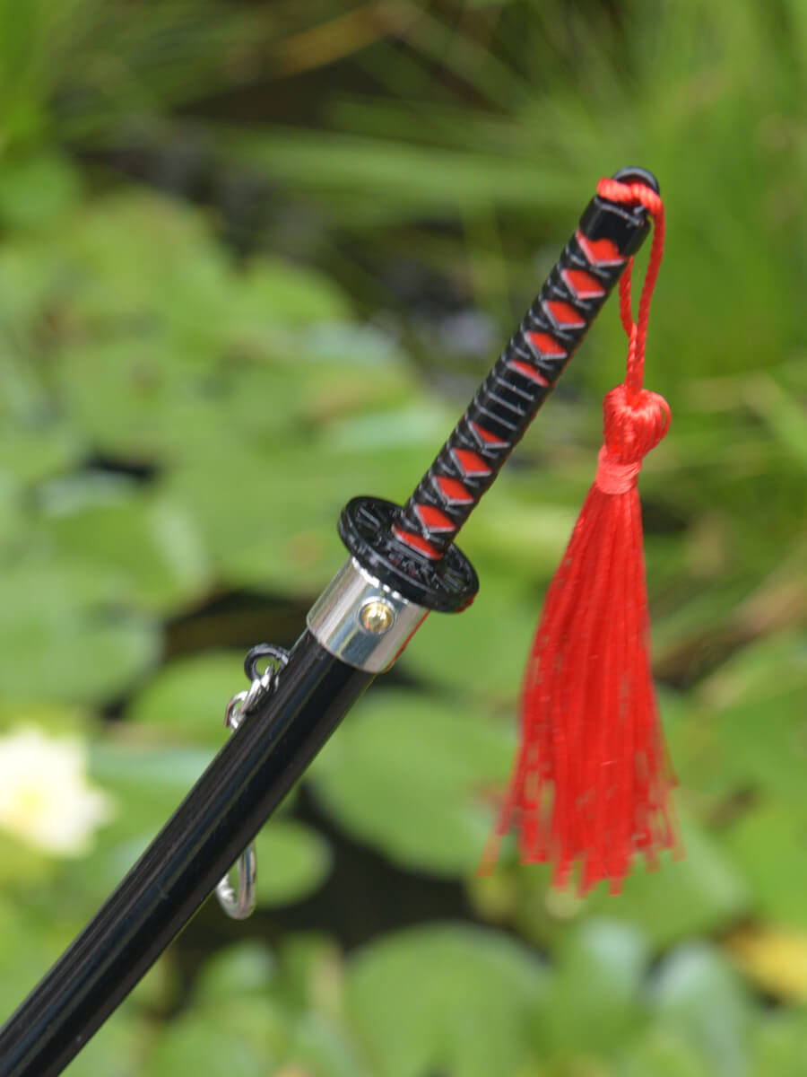 Close-up view from above of Tanjiro miature katana grip and part of the scabbard, showcasing the blade release button.